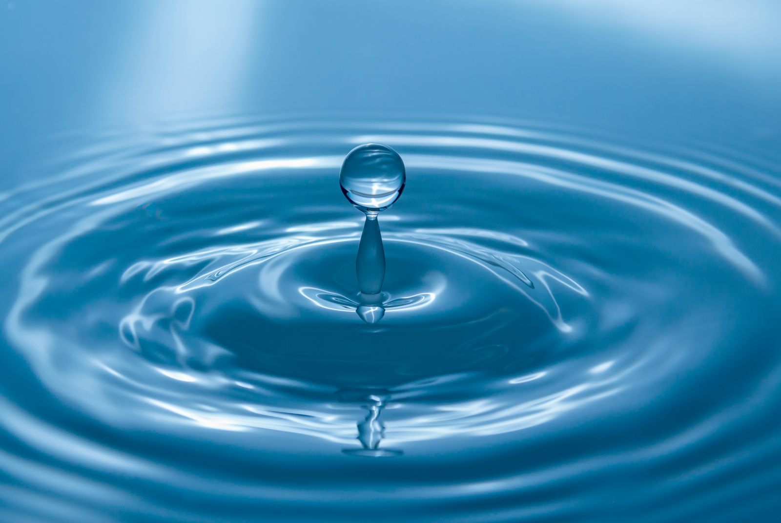 Wassertropfen fällt auf eine ruhige Wasseroberfläche